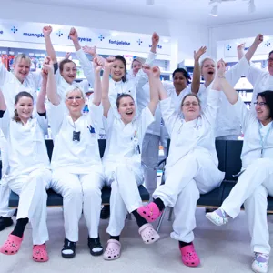 gruppebilde av apotekanmsatte som strekker hendene i været og ser glade ut